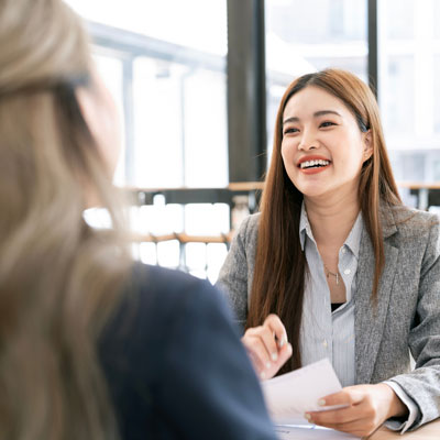Two Business Women Working Together With Laptop While Talking In